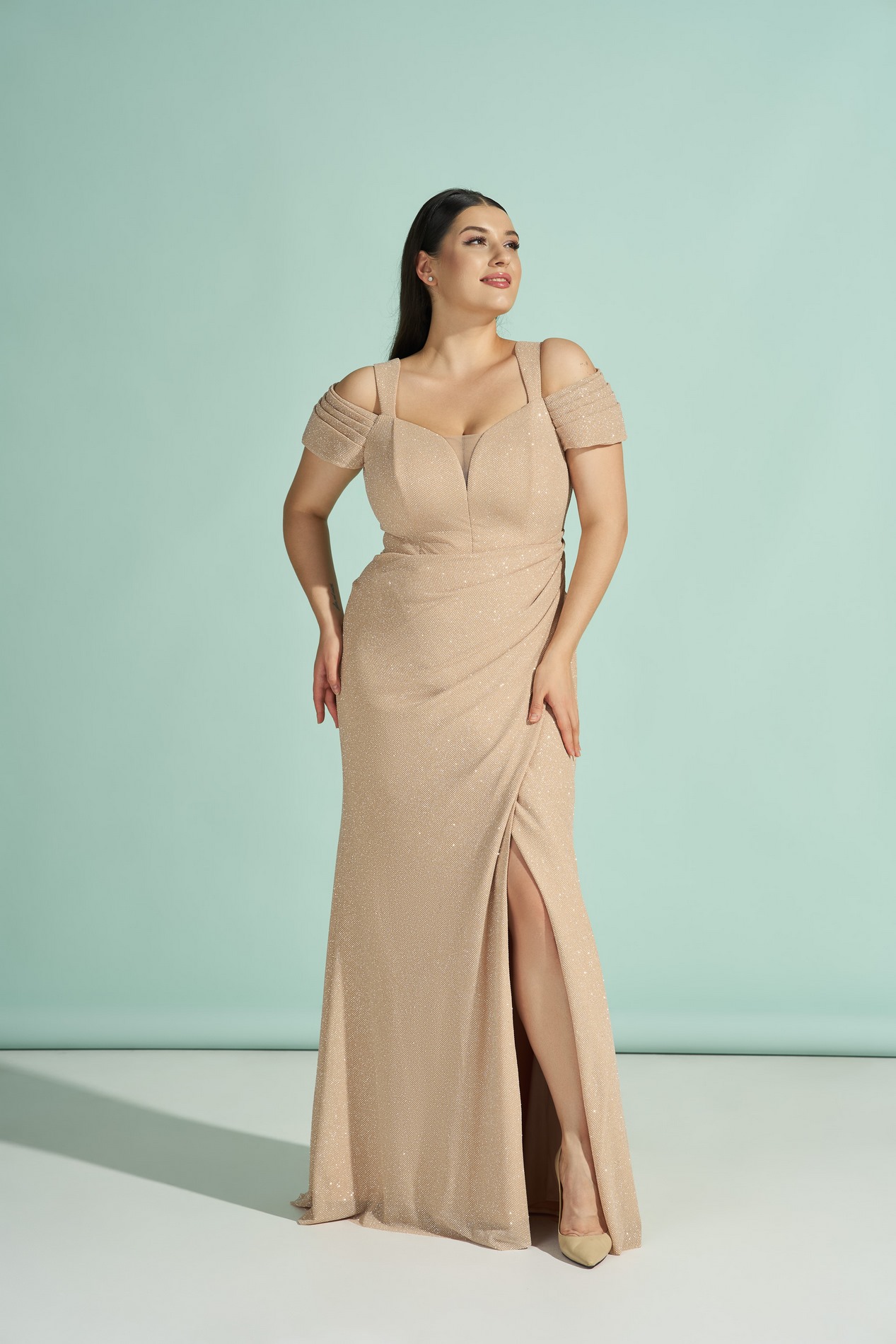 Бежевое блестящее платье со спущенными плечами и разрезом на ноге